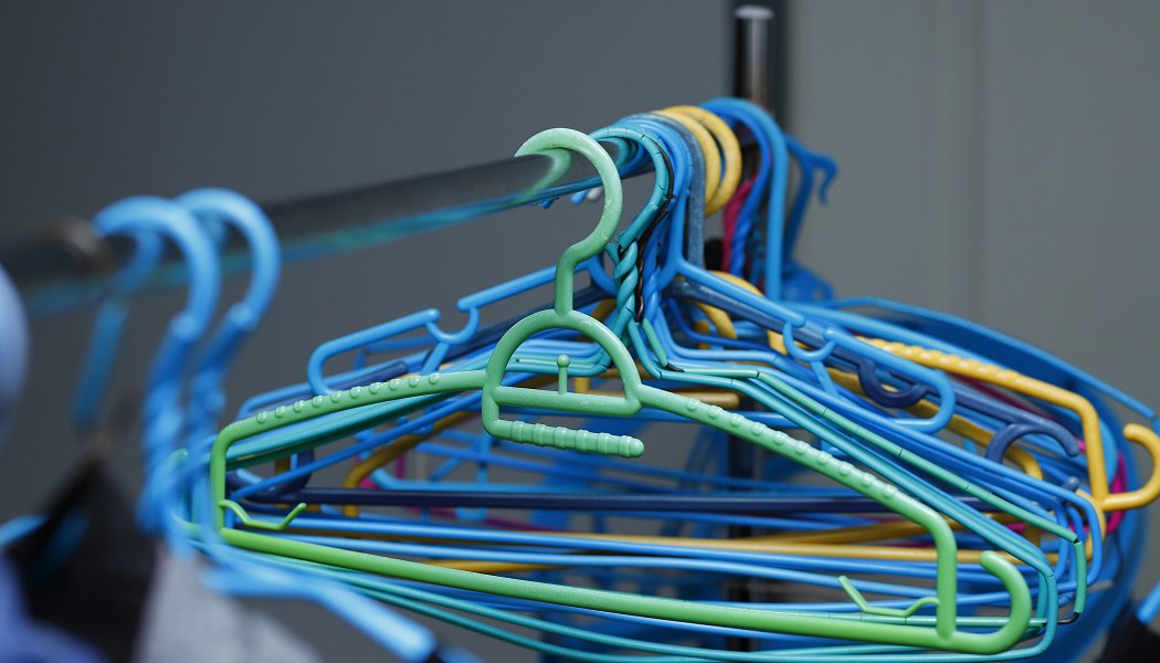 Empty hangers in mainly blue and green colors are hanging on a rag